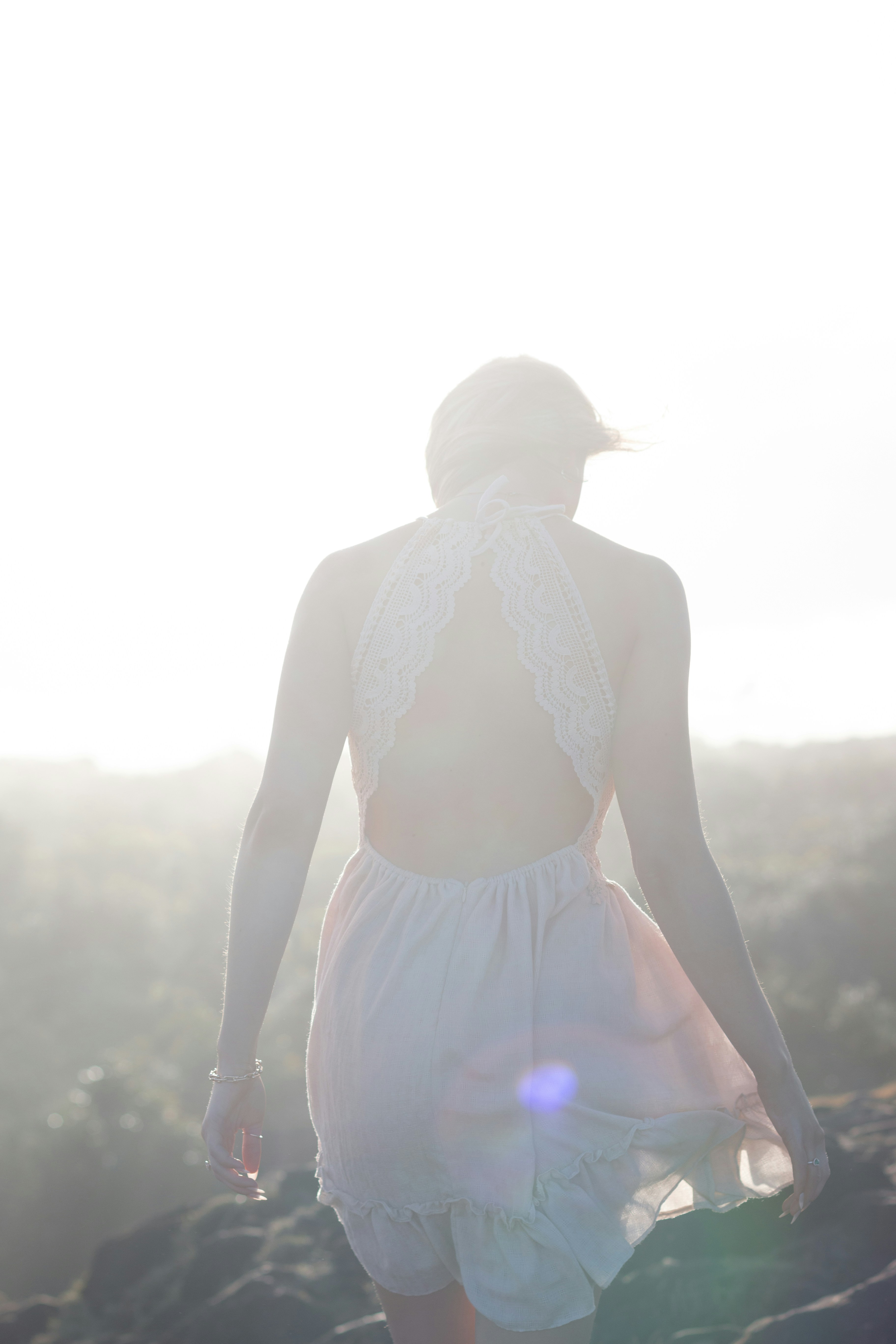 a woman in a white dress walking down a hill