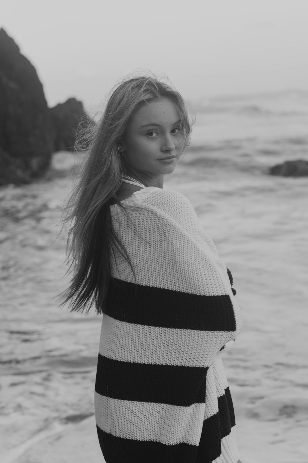 a woman standing on top of a beach next to the ocean