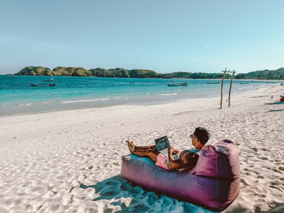 a man sitting on a bean bag on the beach, Relaxing on a beach in Lombok with my laptop out.