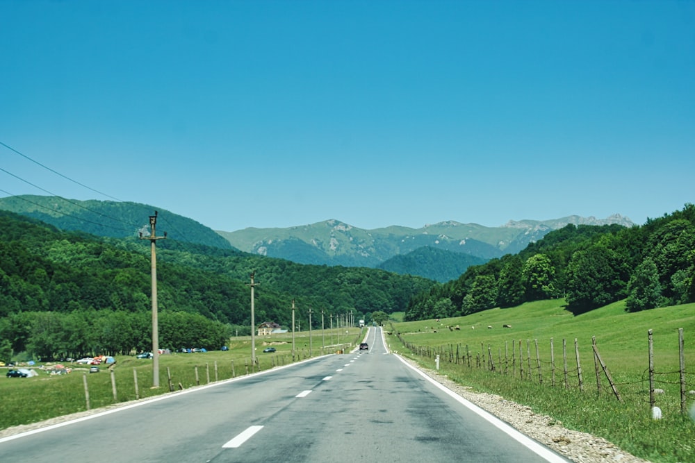 an empty road in the middle of a grassy field