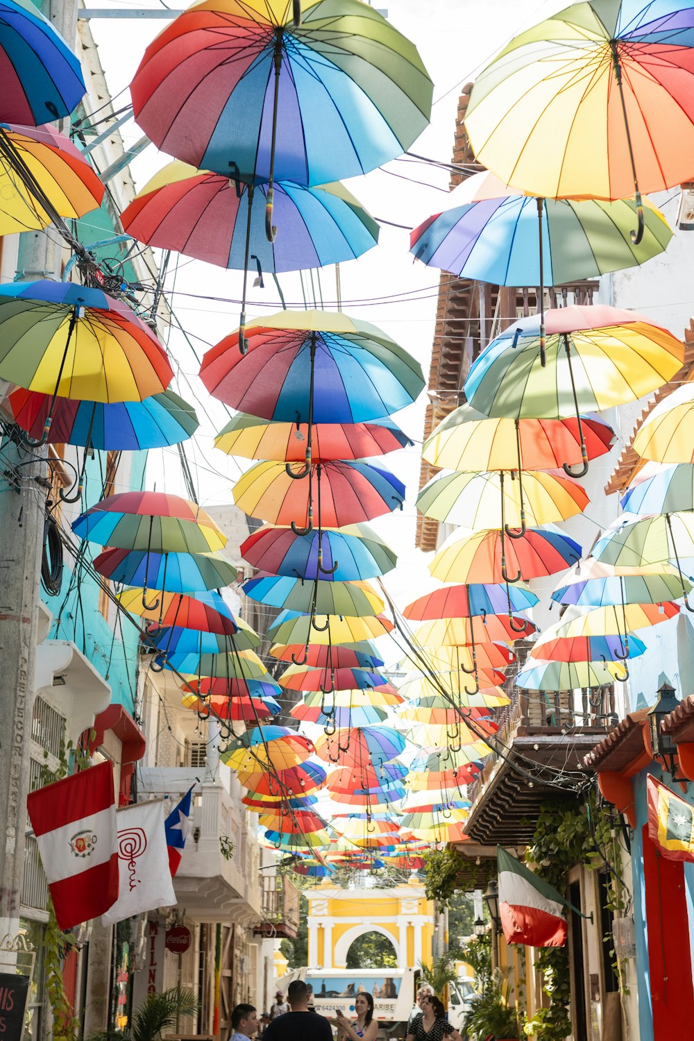 a group of people walking down a street under colorful umbrellas