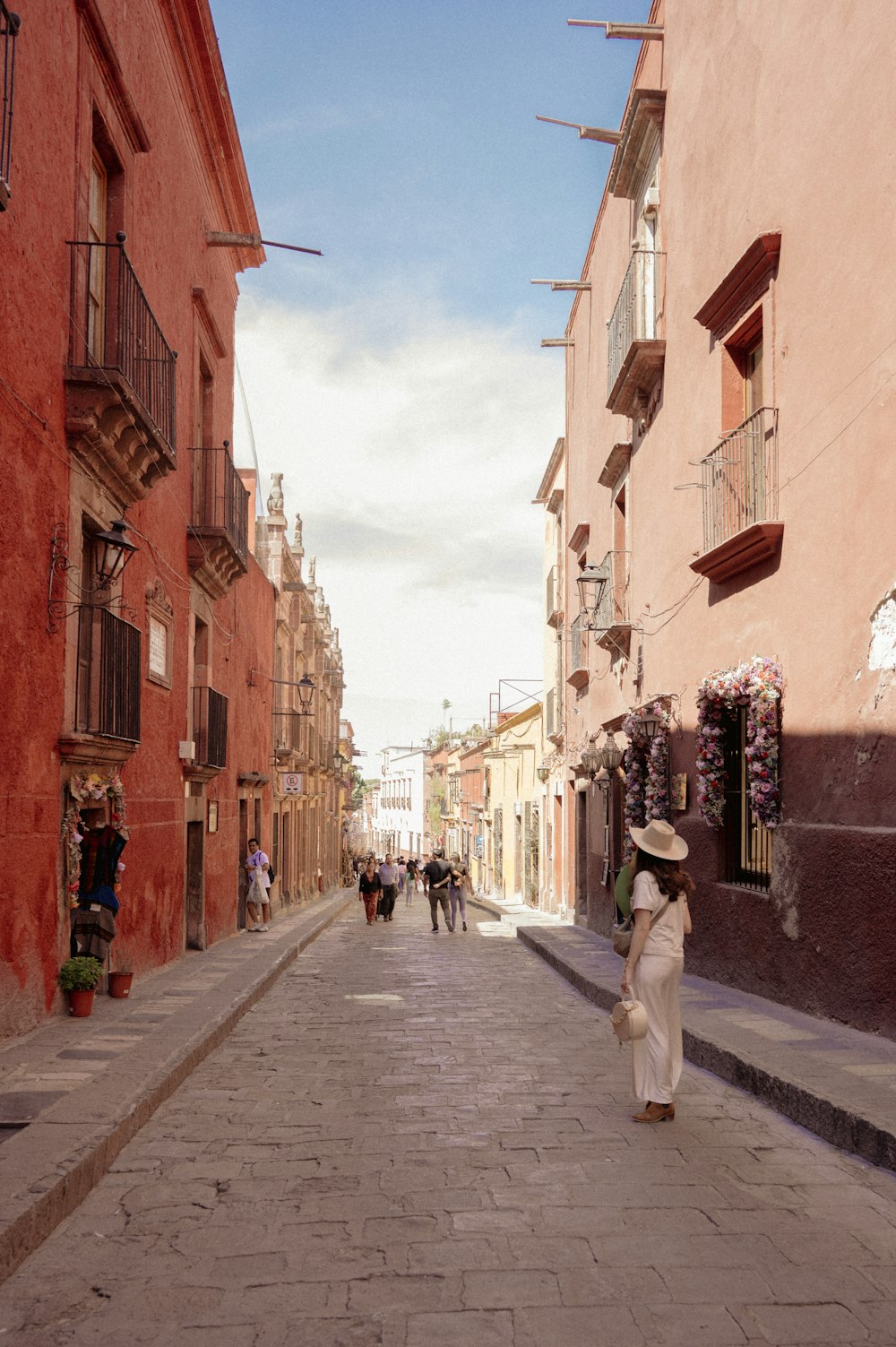 a woman walking down a street next to tall buildings