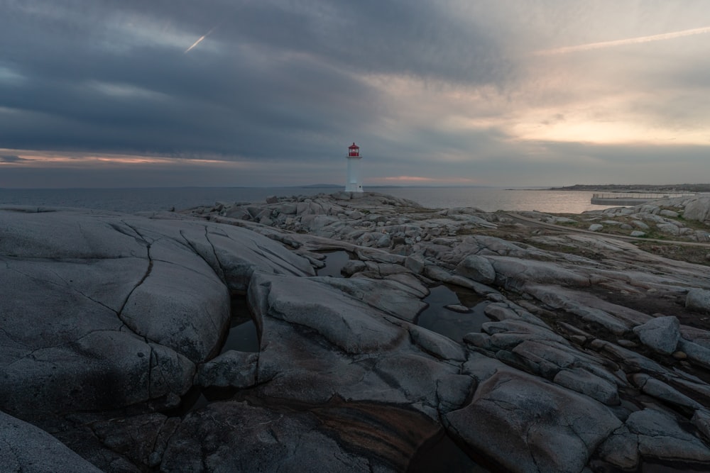 a red and white light house sitting on top of a rocky shore