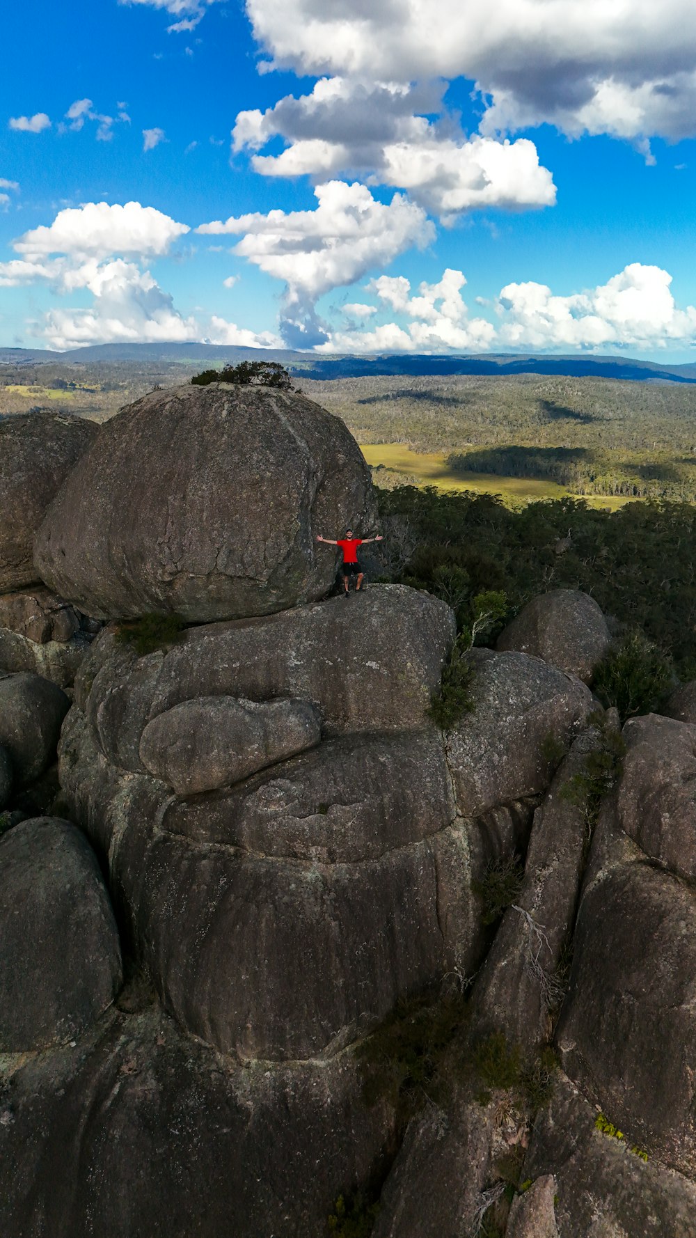 una persona in piedi in cima a una grande roccia