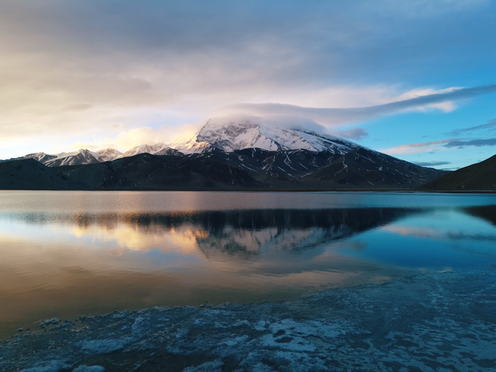 a mountain range is reflected in the still water of a lake