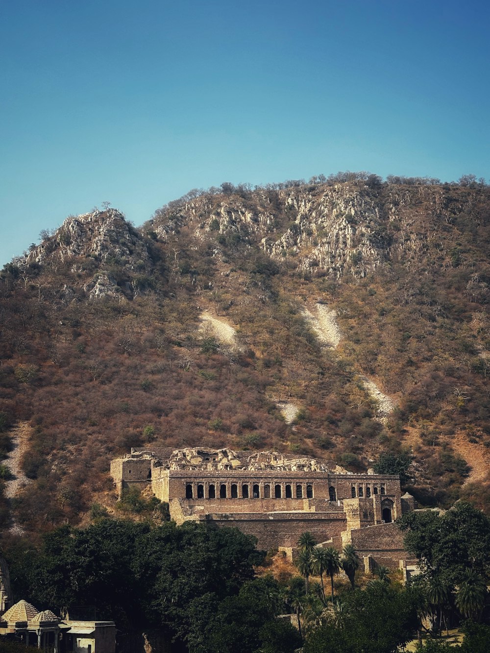 a large building sitting on top of a lush green hillside