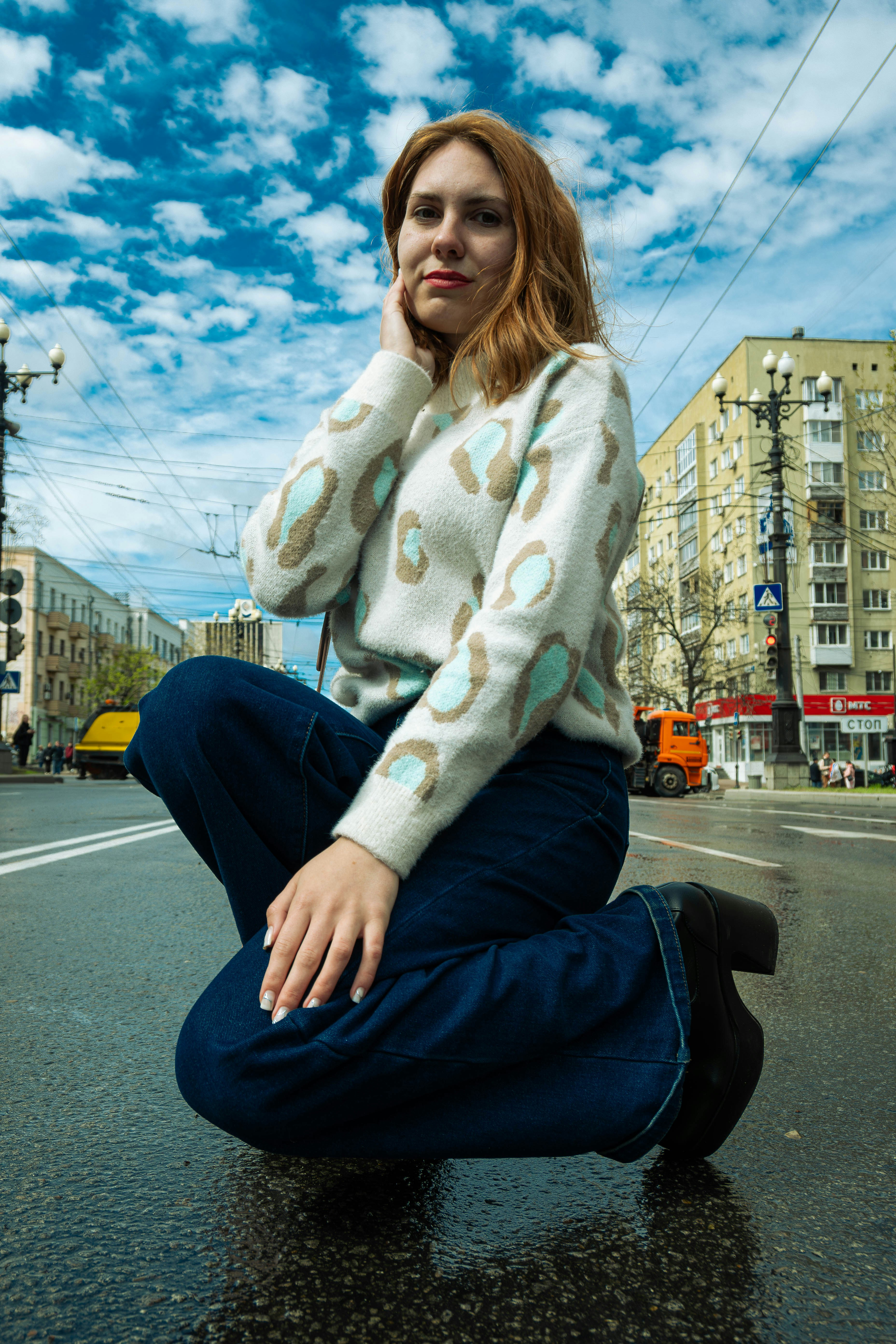 A woman sitting on the ground in the middle of the street photo – Free ...
