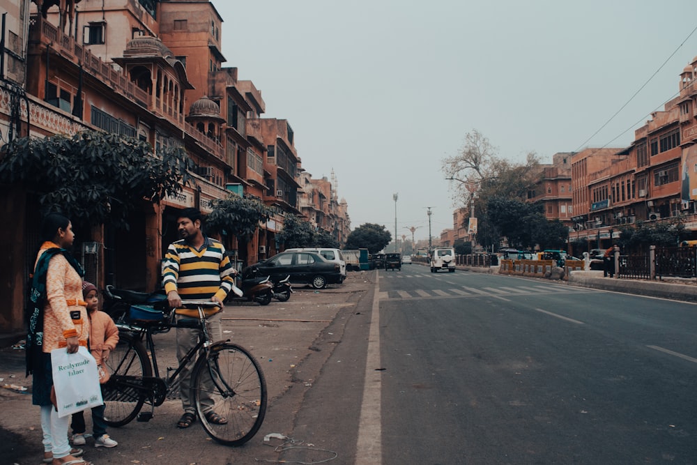 a couple of people standing next to a bike on a street