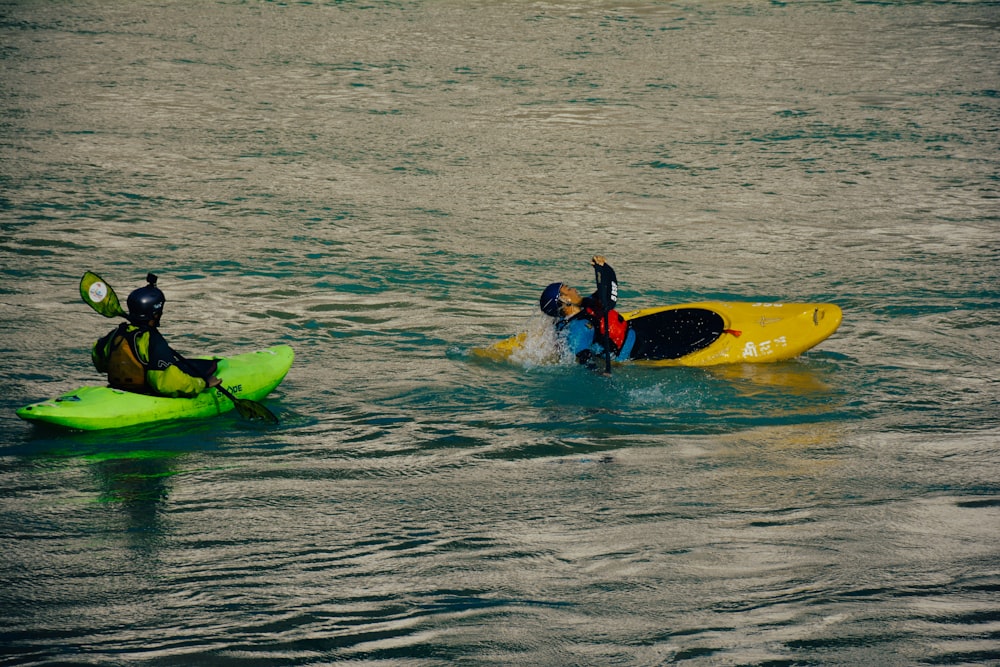 a couple of people riding on top of kayaks