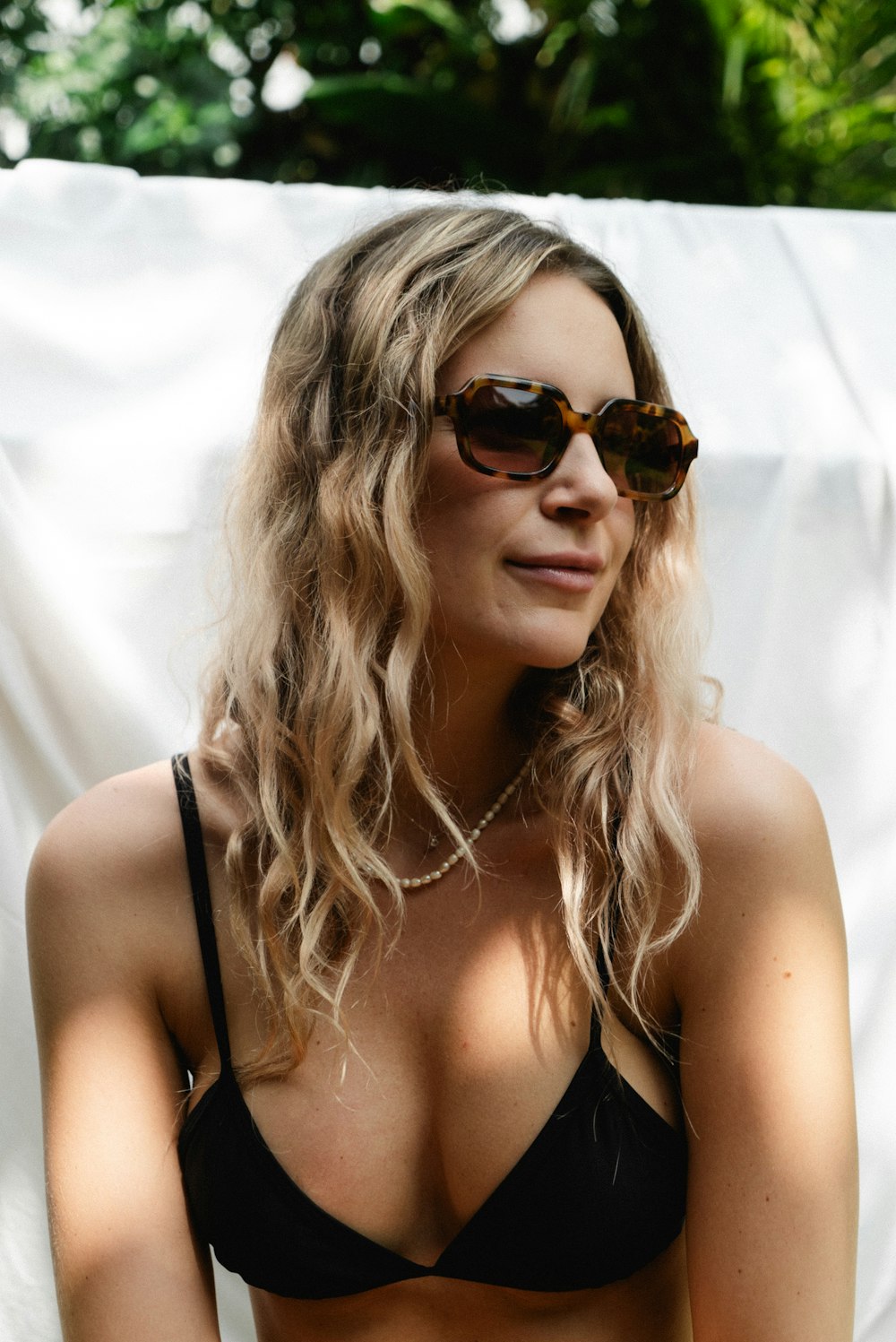a woman in a black bikini top and sunglasses