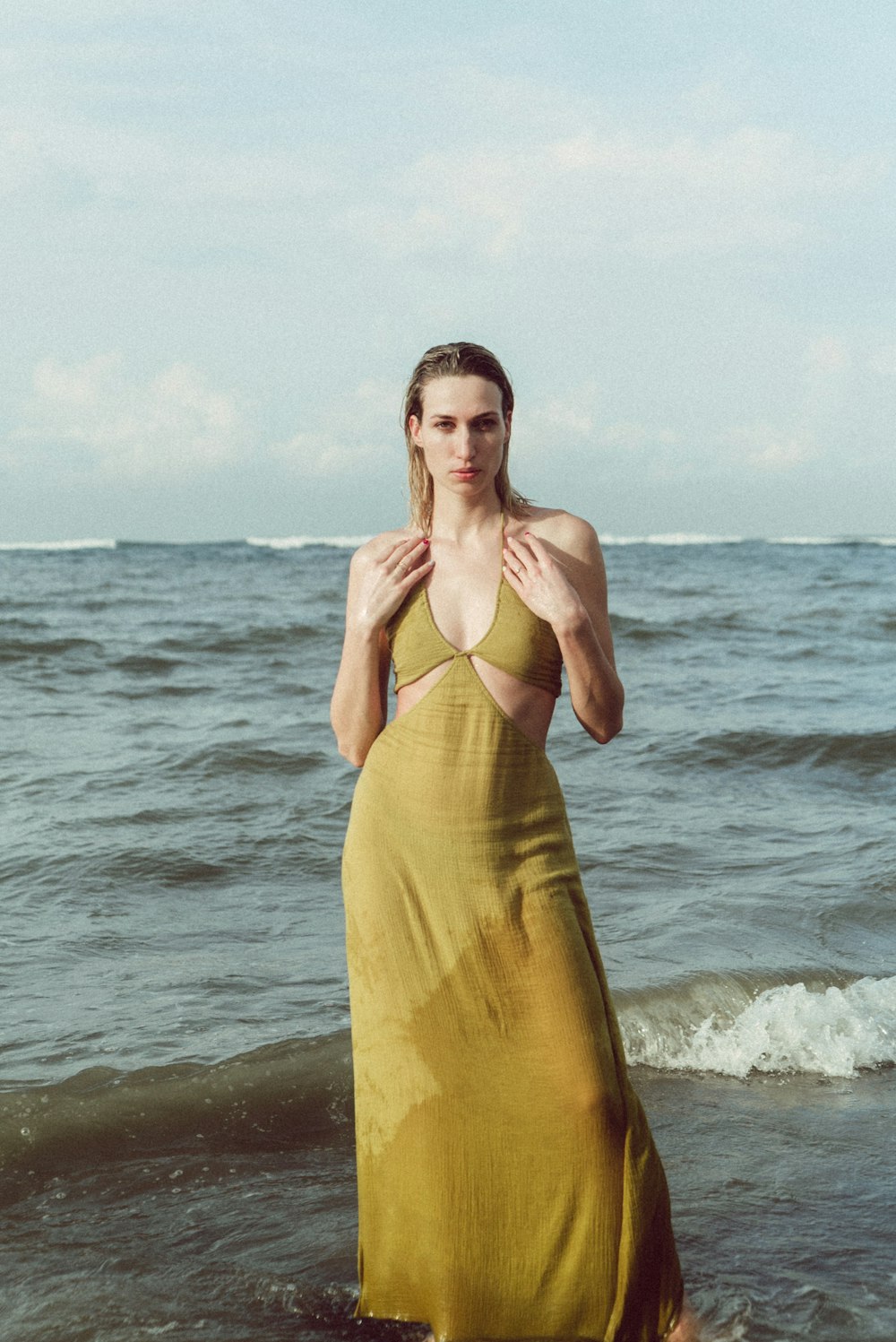 a woman in a yellow dress standing in the ocean