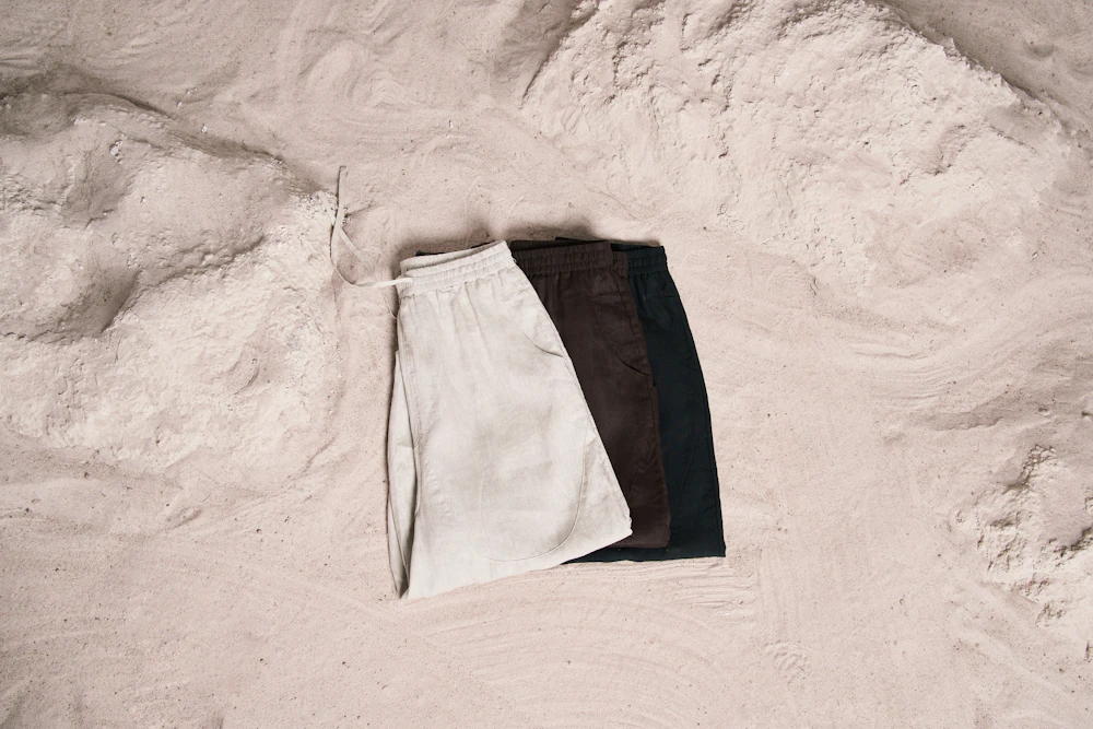 Neutral wide-leg trousers laid flat on sand