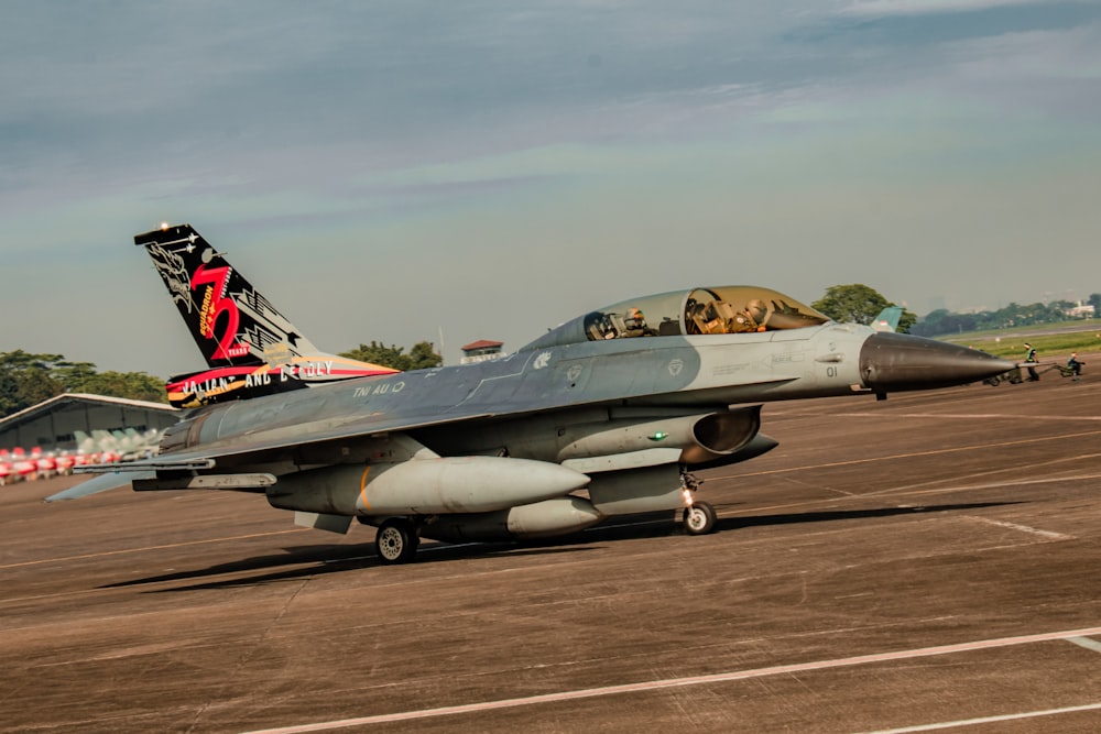 a fighter jet sitting on top of an airport tarmac