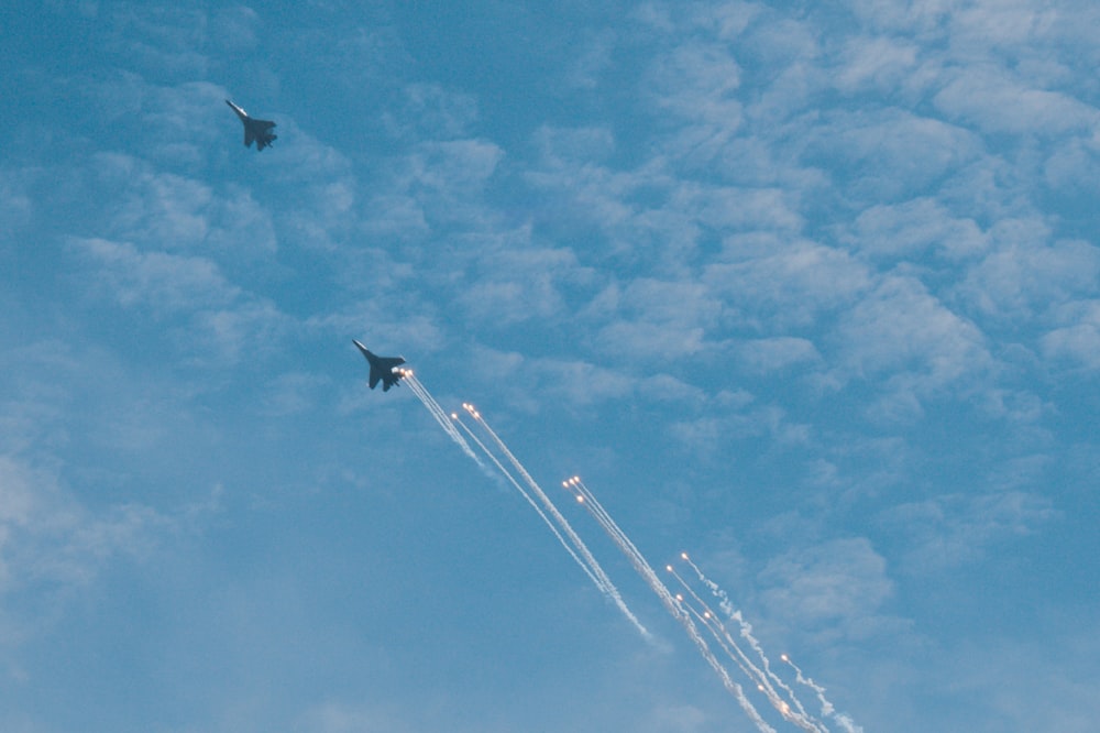 a jet flying through a blue cloudy sky