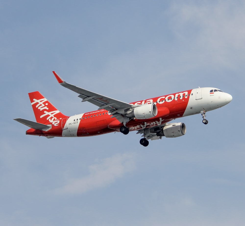 a red and white jet airliner flying in the sky