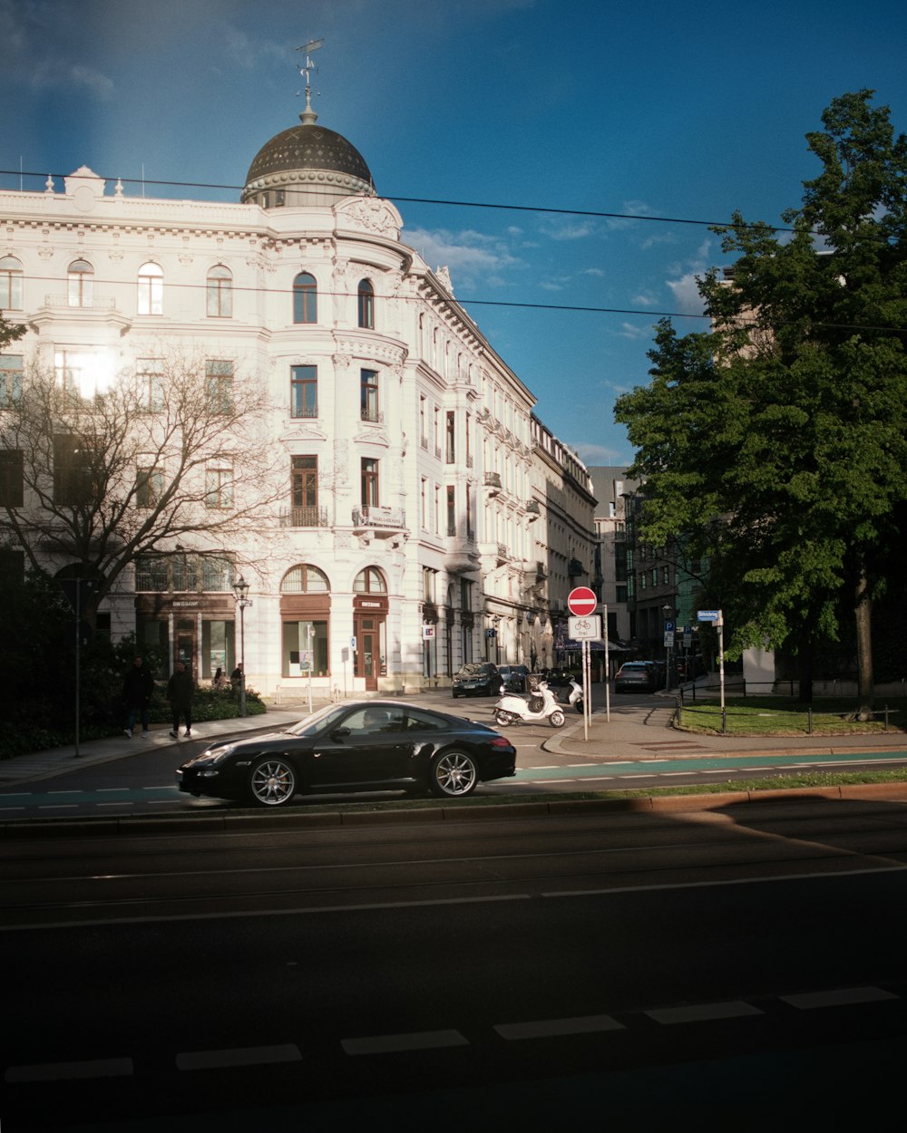 a black car driving down a street next to a tall white building