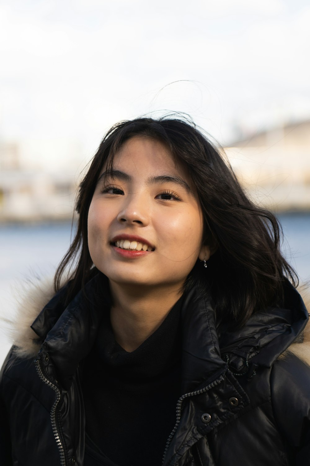 a woman in a black jacket smiles at the camera