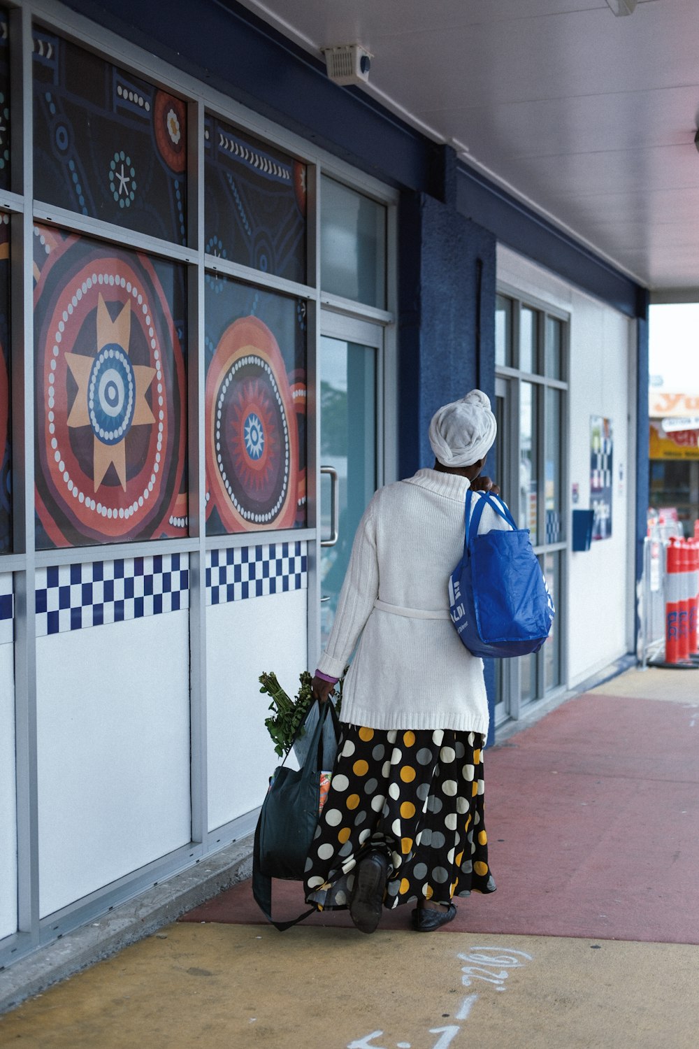 a woman walking down a sidewalk carrying a blue bag