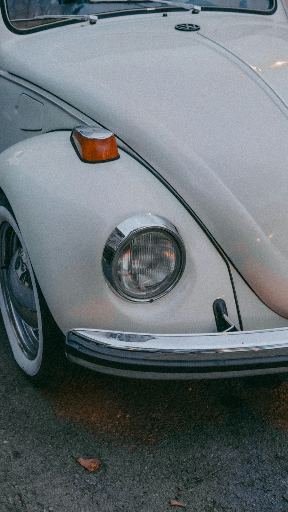 Une VW Bug blanche garée dans un parking