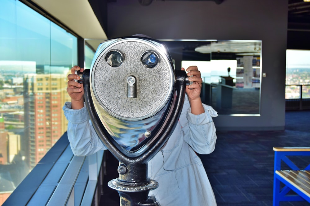 a woman looking through a hole in a telescope