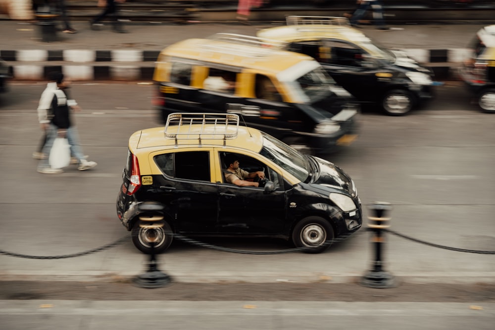 a yellow and black car driving down a street