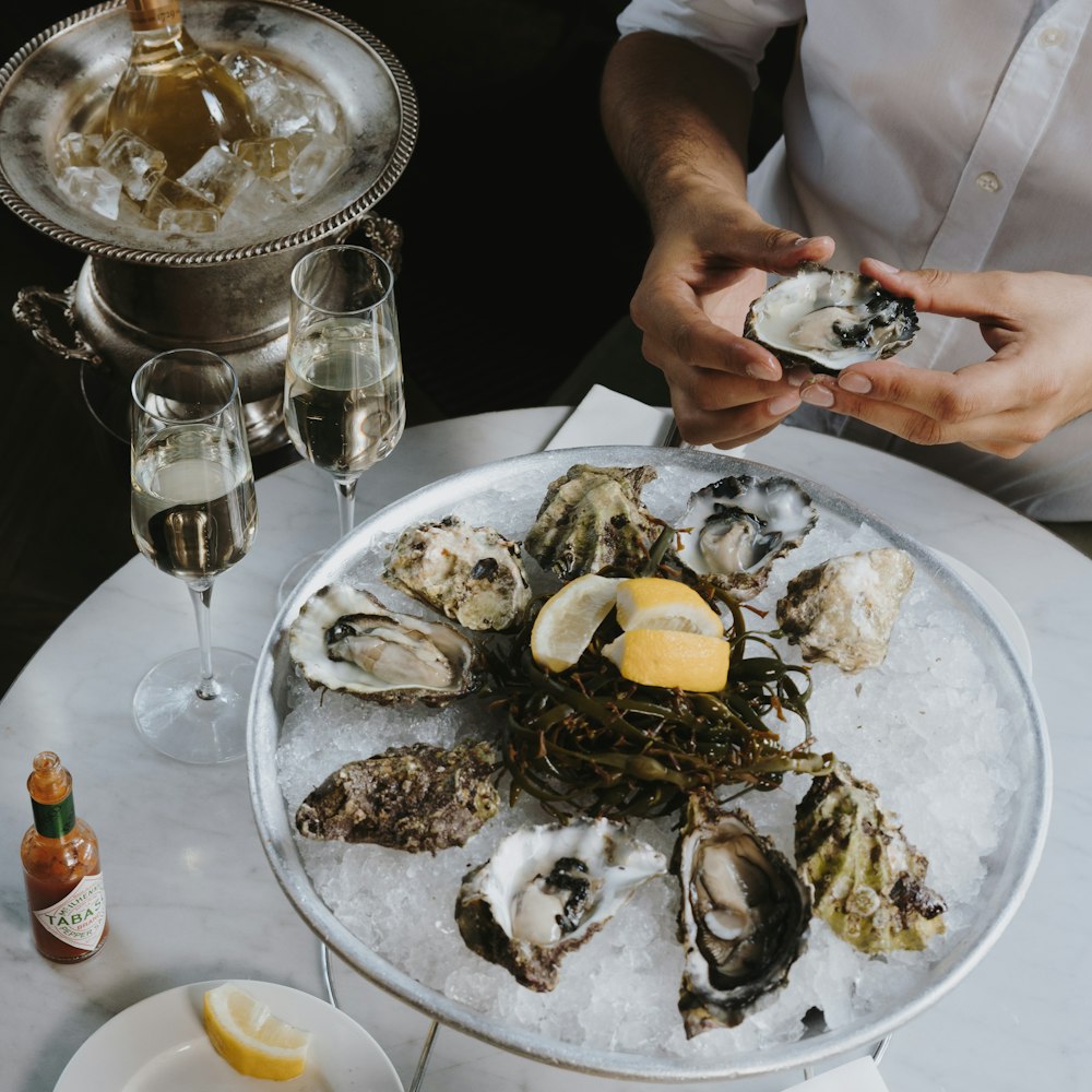 a plate of oysters on a table with a glass of wine