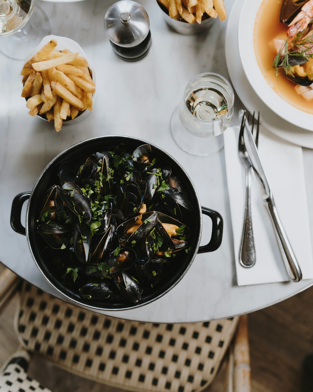 a pot of mussels and fries on a table