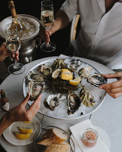 A table topped with fresh oysters on ice and wine glasses at a seafood restaurant