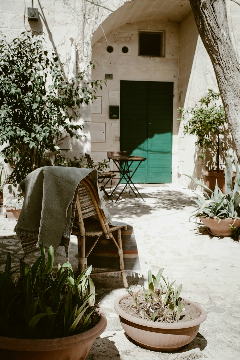 a patio with a chair and potted plants