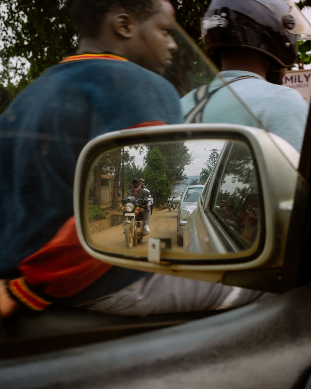 a man riding a motorcycle in the side view mirror of a car