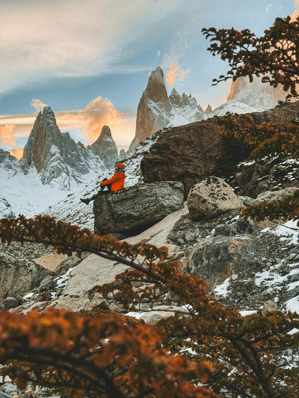 una persona seduta su una roccia in montagna