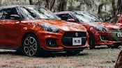 a row of orange cars parked in a forest