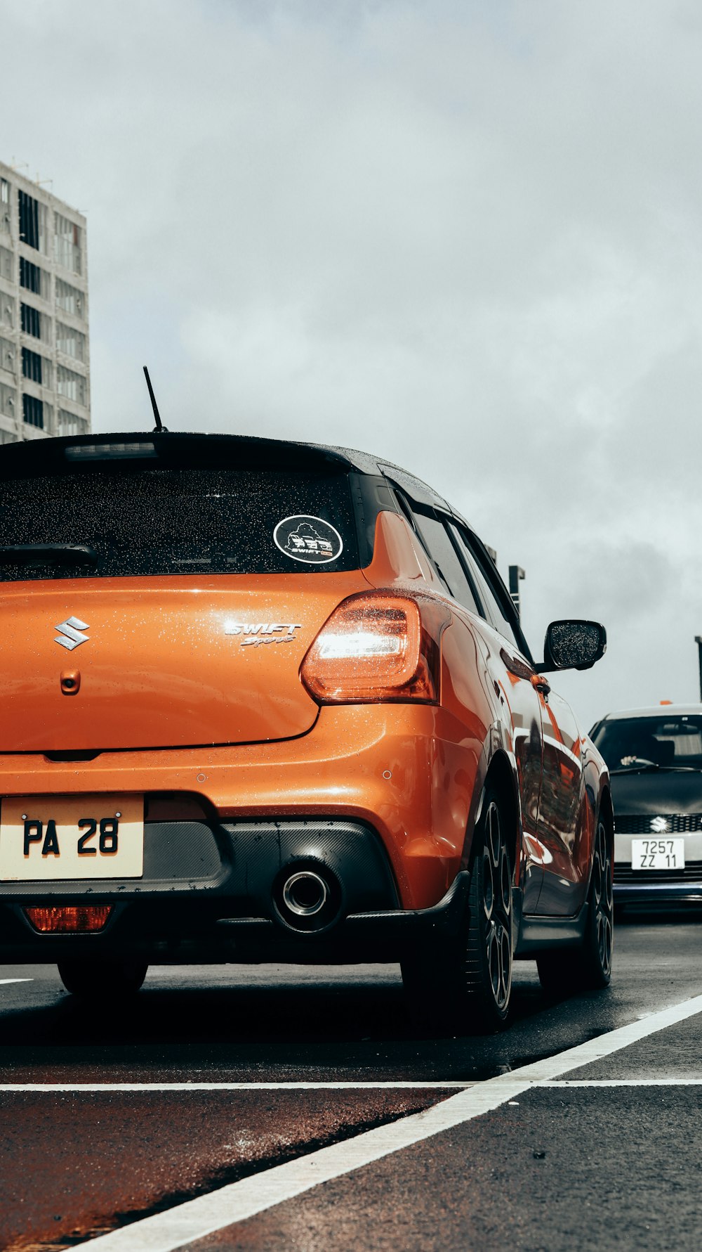 an orange car driving down a street next to tall buildings