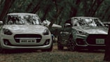 two cars parked next to each other in a forest