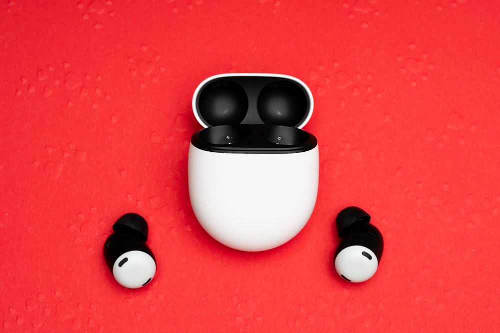a pair of black and white earbuds sitting on top of a red surface
