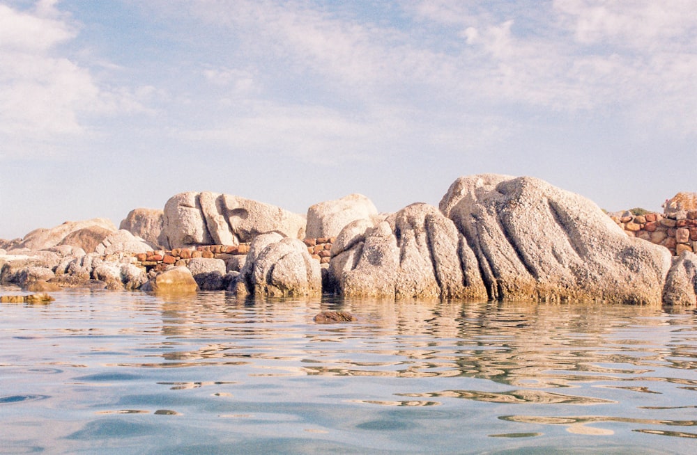 a body of water with rocks in the background