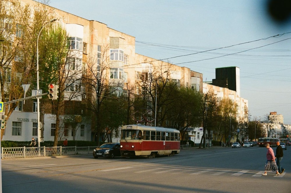 a red and white bus driving down a street next to tall buildings
