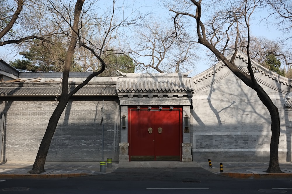 a red door on a brick building with trees in front of it
