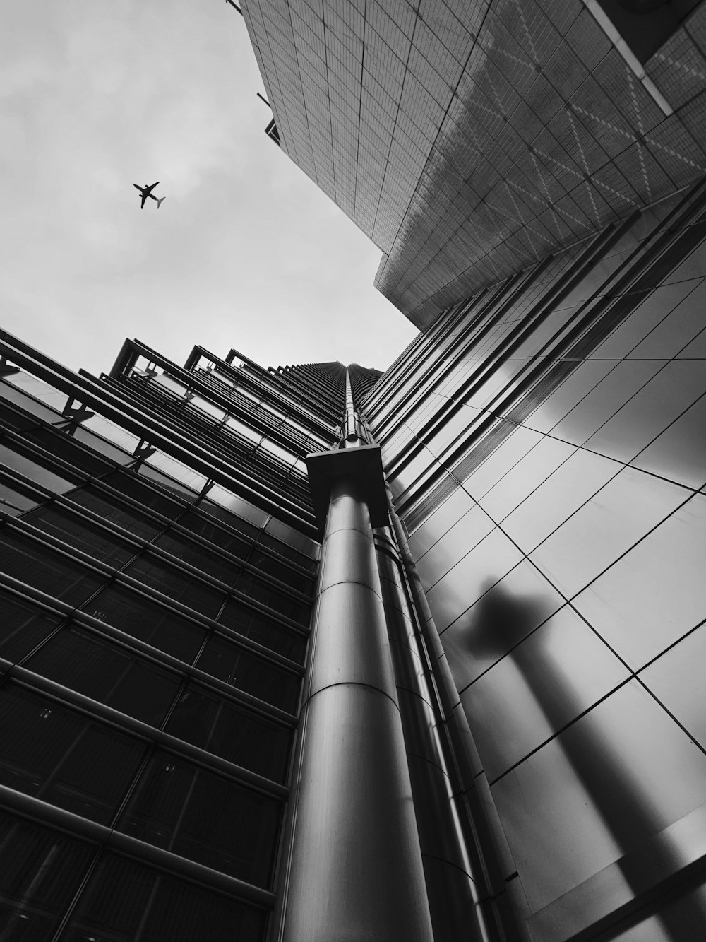 a black and white photo of an airplane flying over a building