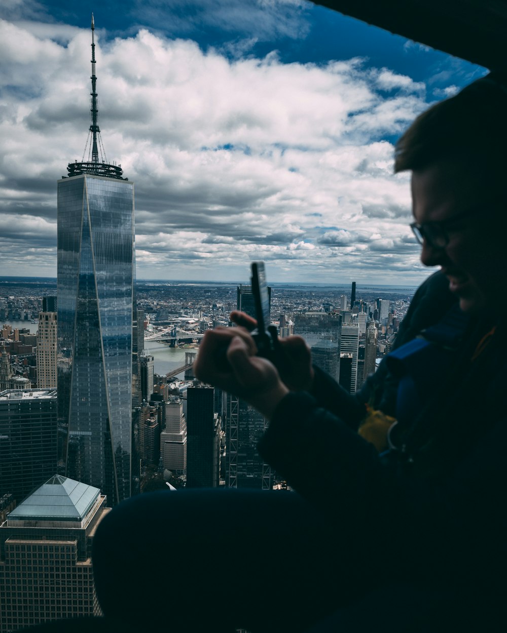 a man looking at his cell phone in front of a cityscape