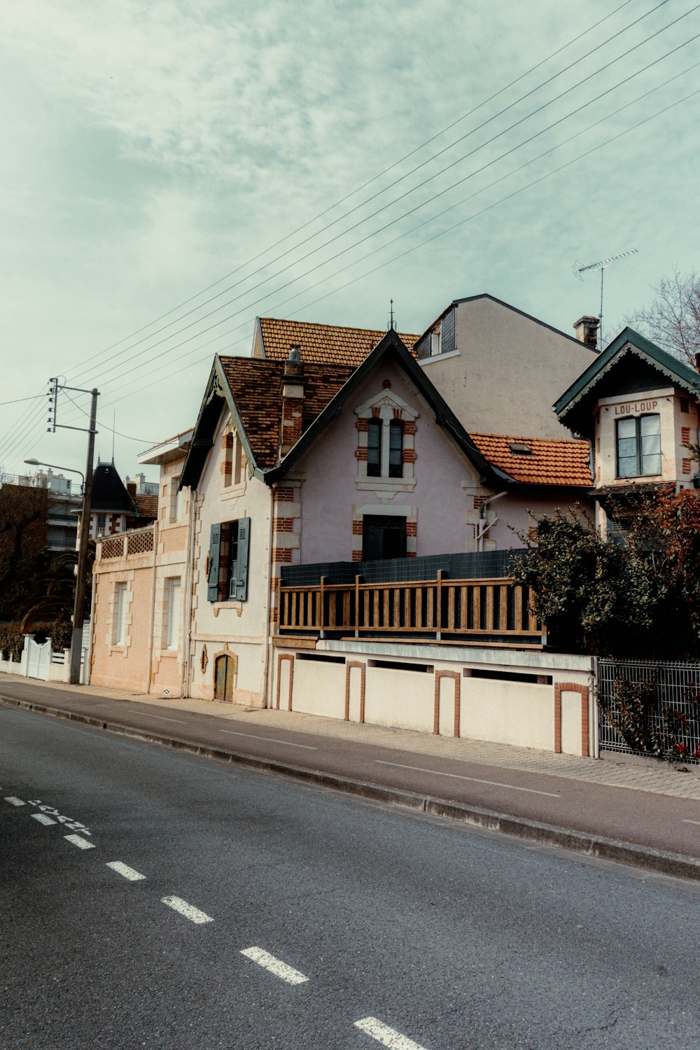 a house with a balcony and a fence on the side of the road