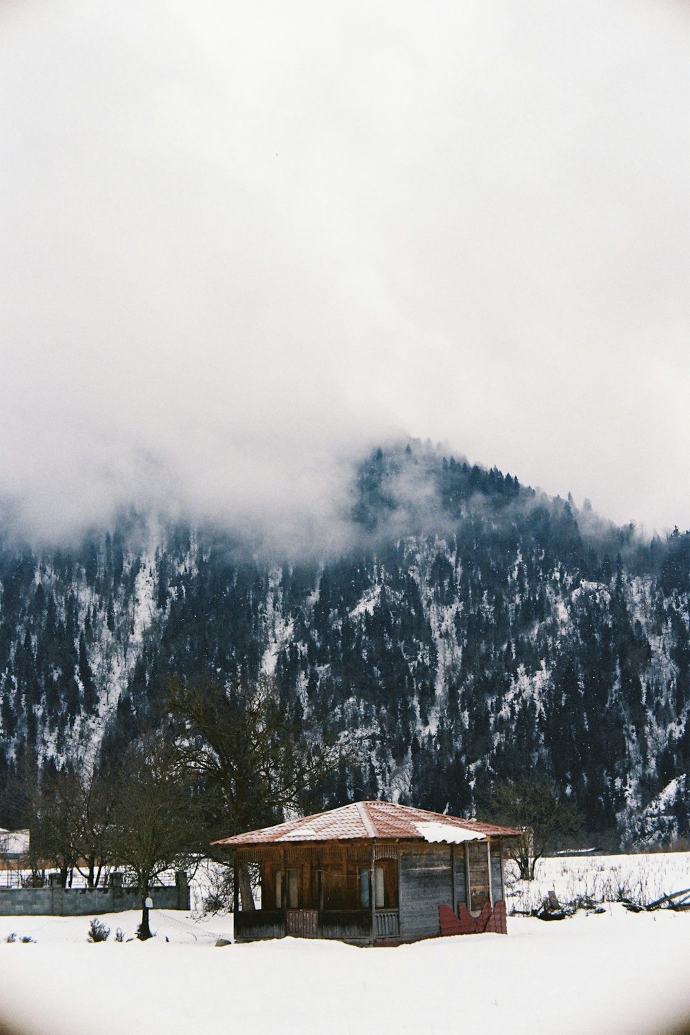 a snow covered mountain with a small cabin in the foreground