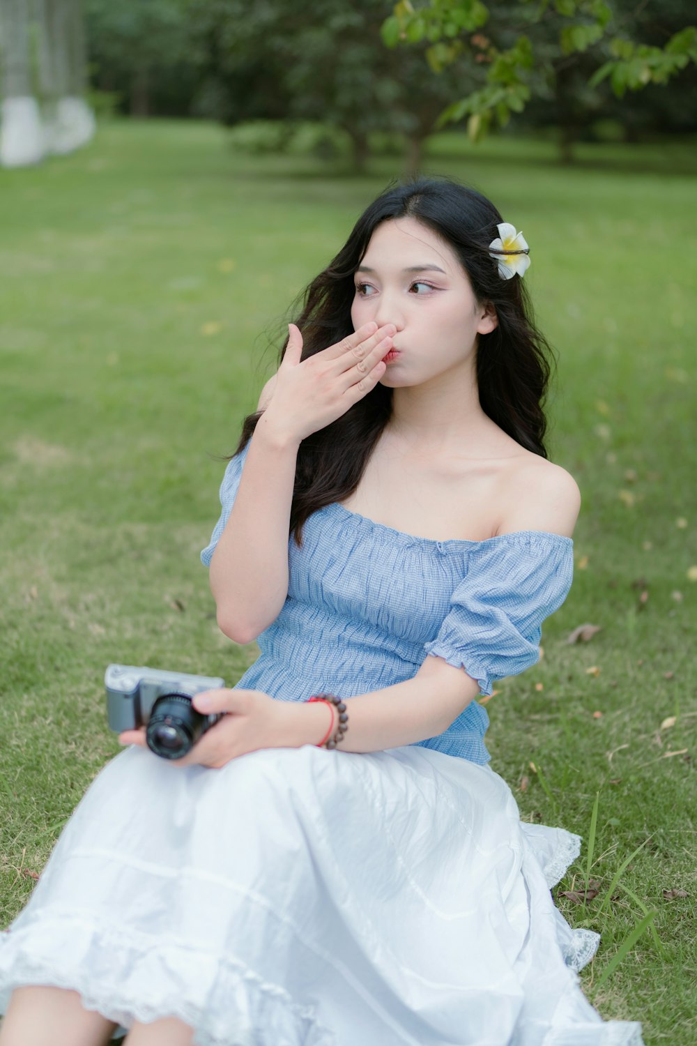 a woman sitting on the grass with a camera