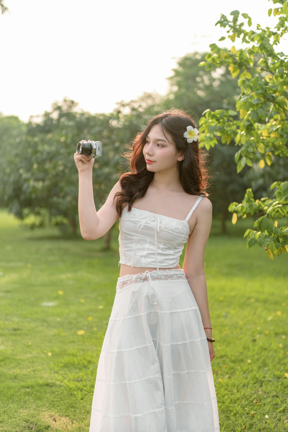 a woman in a white dress holding a camera