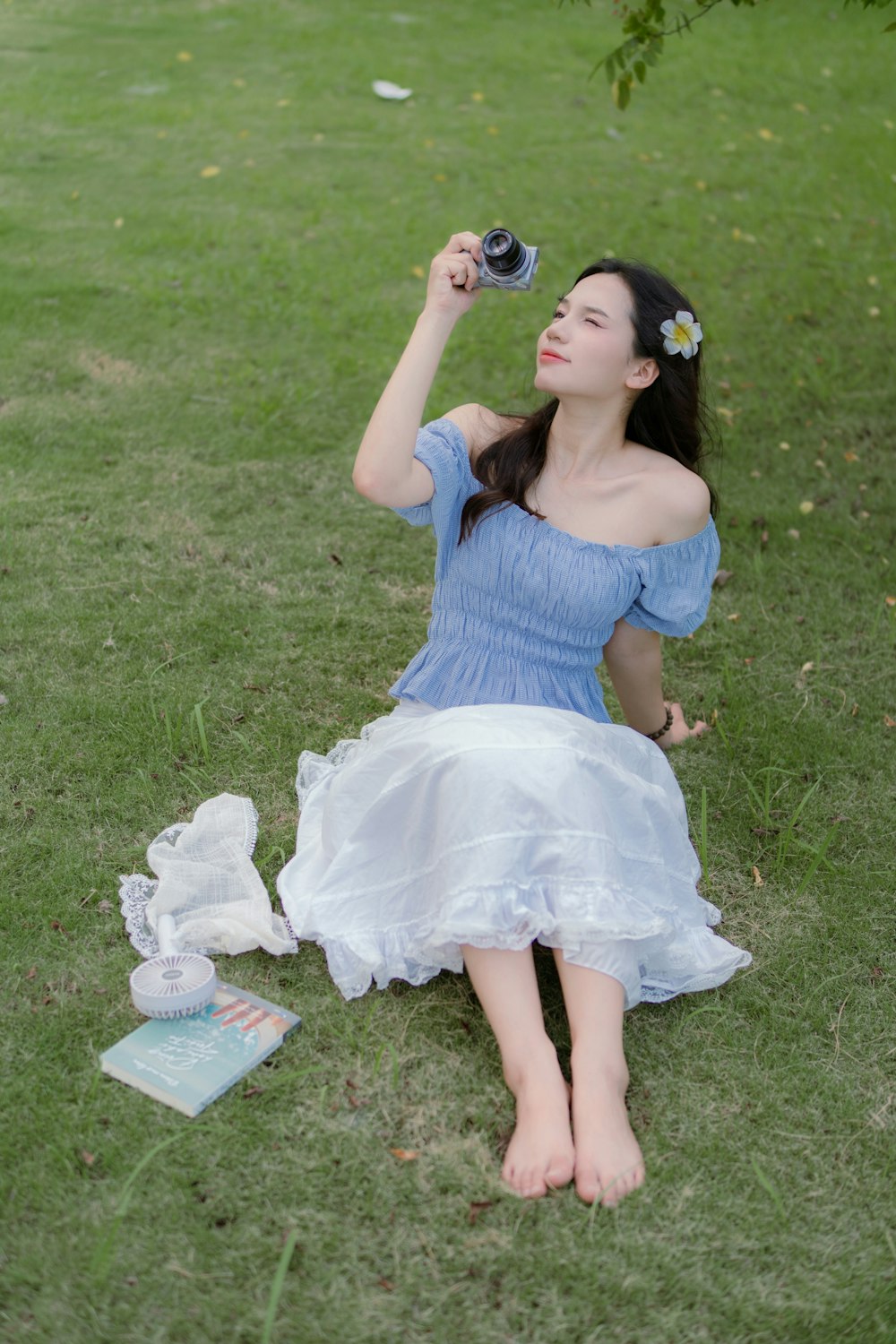 a woman in a blue dress sitting on the grass