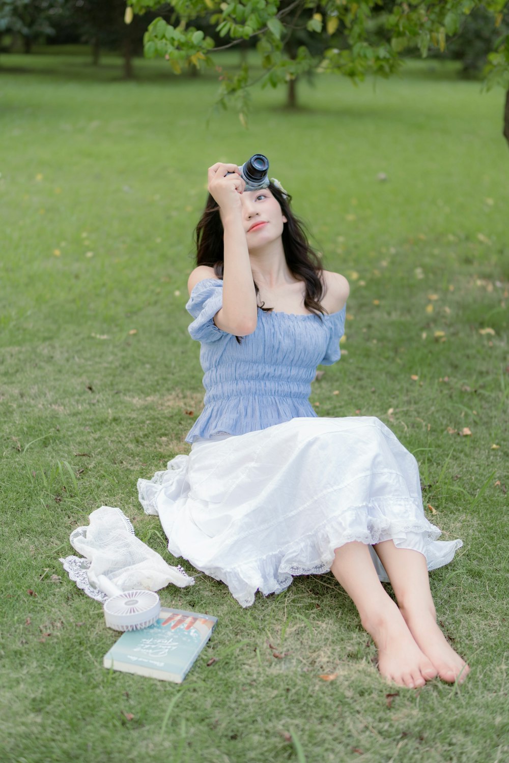 a woman in a blue dress sitting in the grass