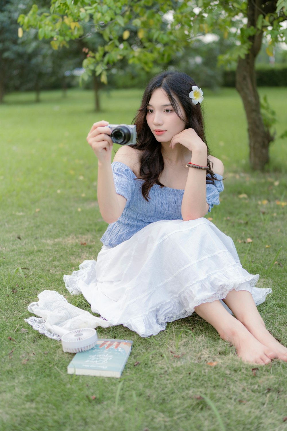a woman sitting in the grass with a camera