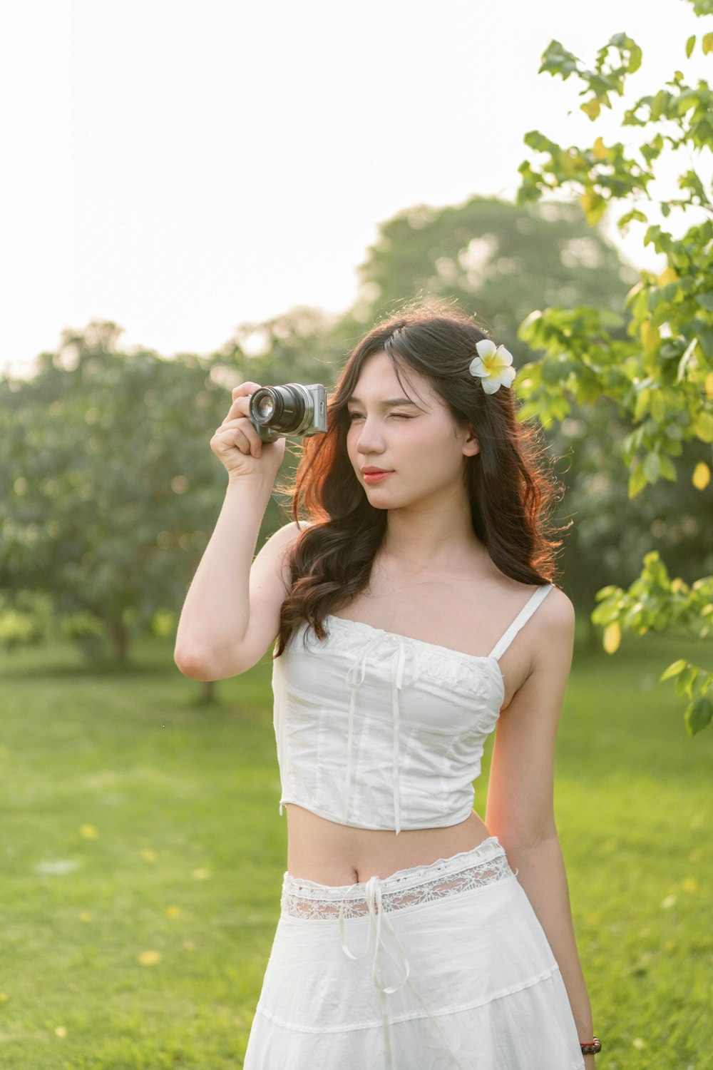 a woman in a white dress holding a camera