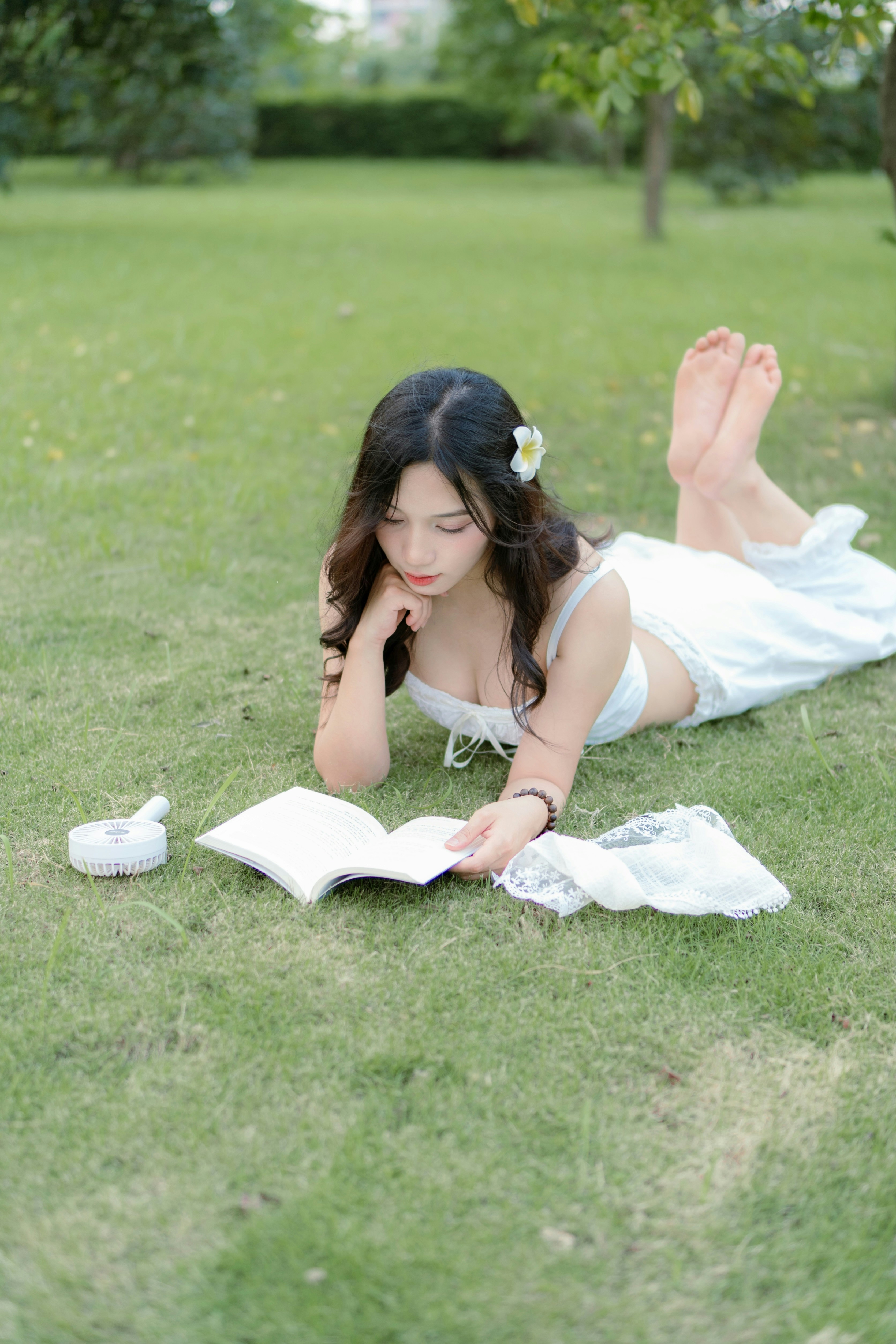 a woman laying on the grass reading a book