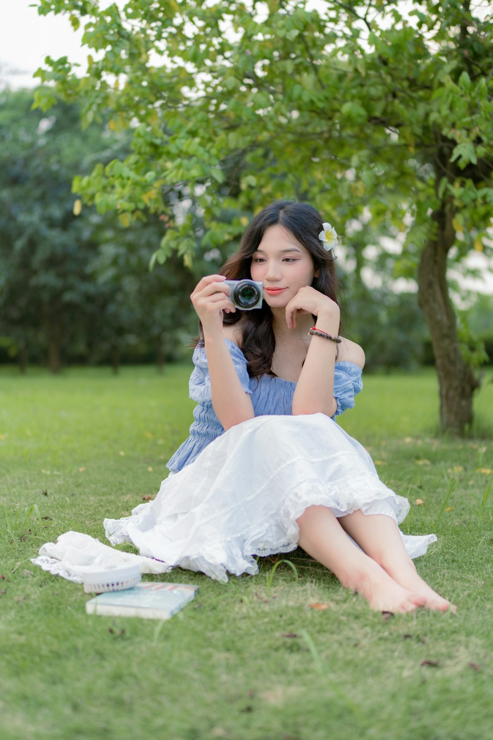 a woman sitting in the grass with a camera